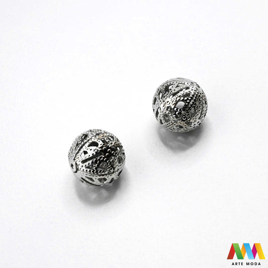 Elegantne metalne filigranske perle u srebrnoj, zlatnoj i nikal boji izložene na površini za izradu nakita. Prikazane su šupljikave i čipkaste metalne kuglice te ovalni filigranski distanceri s raznolikim vintage i orijentalnim uzorcima. Kvalitetan metalni repromaterijal i lagani razdjelnici s izbušenim rupama za provlačenje konca i igala, namijenjeni za izradu unikatnih narukvica, visećih naušnica i bogatih ogrlica u kreativnim DIY radionicama za izradu ručno rađenog modnog nakita arte moda repromaterijali